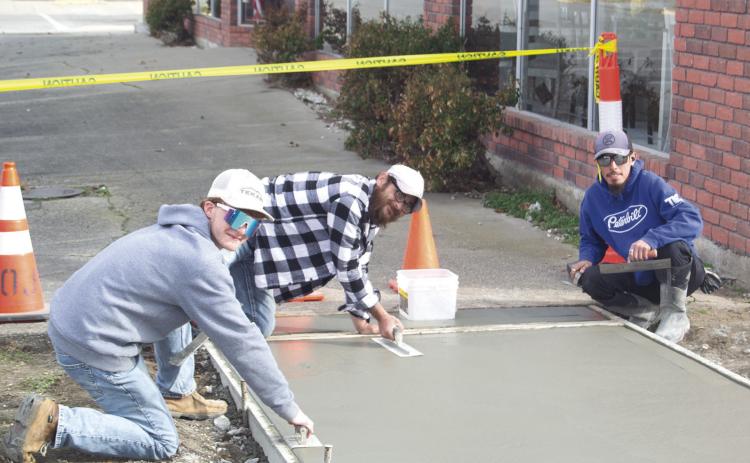 Construction crewmembers Andrew Heinlein, Johnathan Pinnegar, Ruben Reyes, and Robert Pinnegar (not pictured) are laying down the concrete for the new sidewalk between Westco and Tique-A-Bou. The up-keep of the town’s sidewalks is part of the City Council’s plan to improve the town’s upkeep. News Report photo by Shawn Churchill.