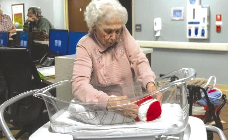 Columbus resident Ruby Wright places the red and white Valentine’s Day cap on Afredo Rodriguez. She has created over 2,000 caps for babies at Freeman Hospital in Joplin, Mo. She is working her way toward 3,000 now. Courtesy photo.