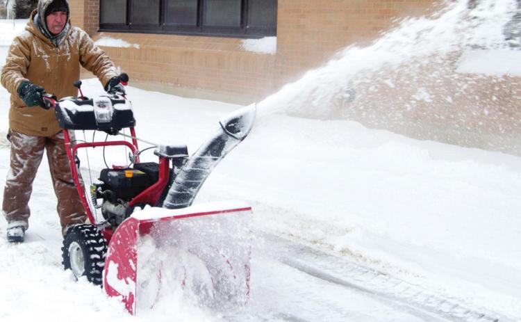 Columbus USD 493 Employee D. G. Ellison operates a hand-pushed snow blower