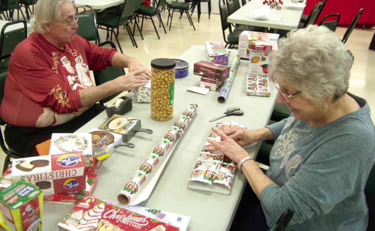 Preparing gifts for the Ugly Holiday Sweater contest winners were Steve Langerot and Donna Renn. The sweater show was held Sunday evening at St. Bridget’s Parish Hall.
