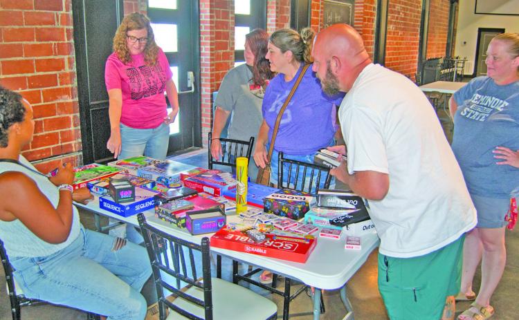 The Columbus Library sponsored Game Night drew families to play several games. The event held at the State Theatre Event Center. Librarian Lauren Dainty hands out games to the players.
