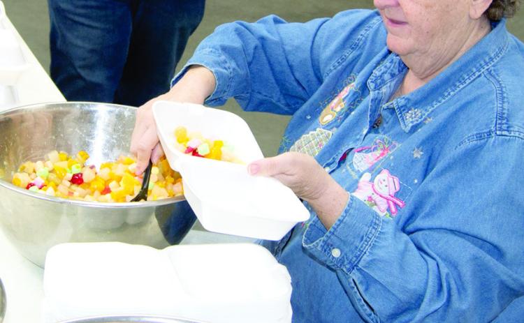 Robin Jones fills fruit cocktail bowls Saturday morning before the crowds arrived. She has been providing a Christmas community dinner for 30 years. Which she says she could not do without a lot of helpers.