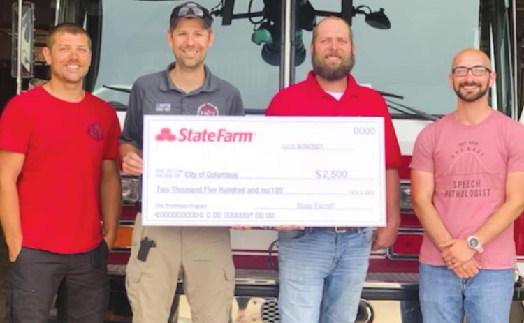 Fire fighters Cody Burton and Fire Chief Steven Burton accept a check
