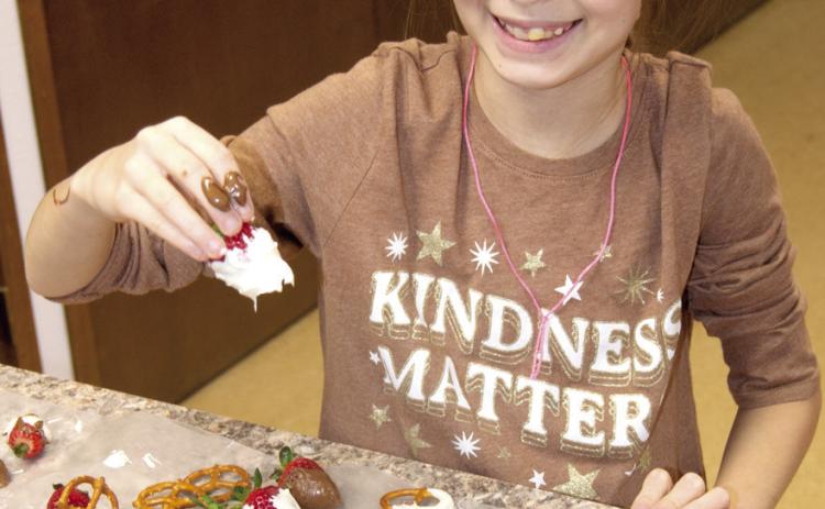 The 4-H Winter Fun Camp Day kept youngsters busy with crafts such as Angelina Capron dipping strawberries in chocolate for a Christmas treat. The day included crafts, cooking, robotics and more.
