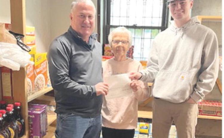 Gene Hamilton and Cameron Draeger with Optic Communications presented Sharon Draeger at the First United Methodist Church food pantry with a $1,000 donation. Courtesy photo.