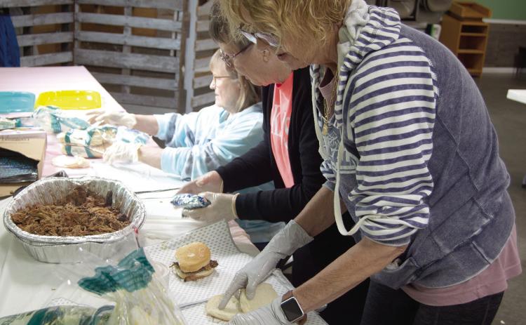 Workers were busy at the pulled pork fundraiser for Jenny Shilts recently. Marilyn Epler, Janice Maxton and Karen Karsten were preparing the sandwiches. News Report photo by Tanya Woolsey.