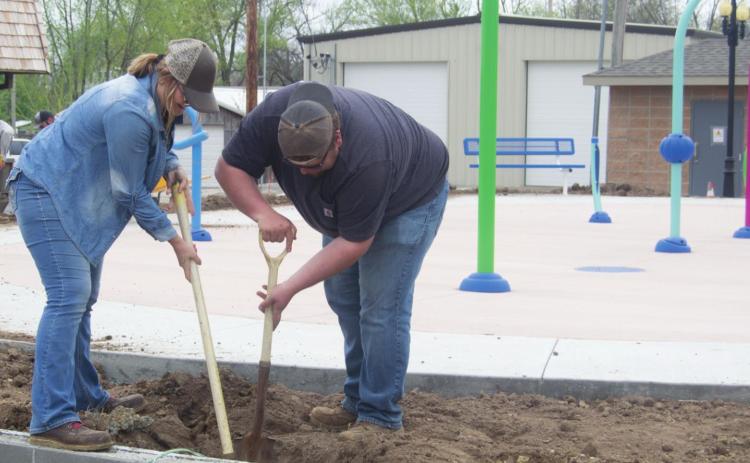 Columbus Parks and Property employees Kasie England and John Shallenburger worked to prepare the ground surrounding the H and H Splash Pad. The attraction opens to the public with an official celebration May 20. Photo by Jacob Spencer.