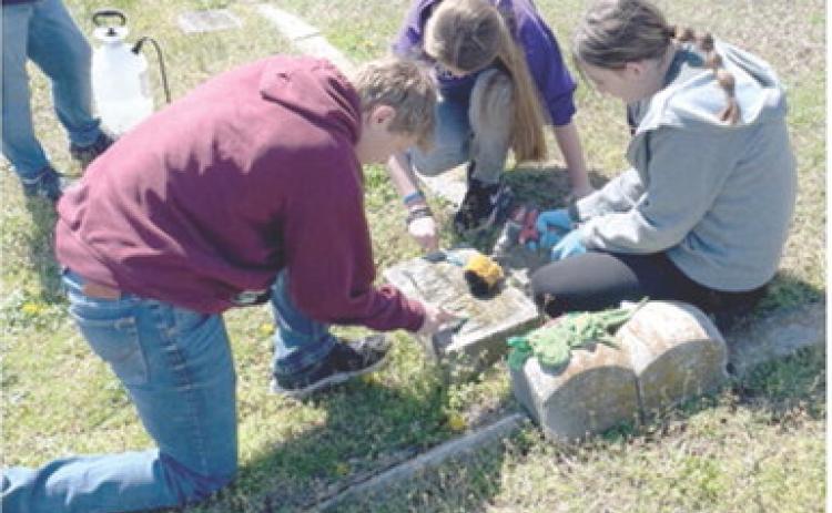 Seventh grade students at Southeast Middle School participated in a day of service April 8. Gavin Potts, Kylee Emerson, and Kinzey Mitchell were cleaning headstones at Cherokee Cemetery. Students also picked up litter on Highway 7. Sons and Daughters of the American Revolution assisted with supplies explained historical preservation techniques. Courtesy photo.