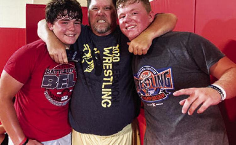Titan Wrestlers Kash and Kanyen Smith are wrangled by Coach Randy Roark, 1992 Columbus Unified High School Graduate, after putting in time on the mat at the wrestling clinic in the high school gymnasium, July 19. Courtesy Photo.