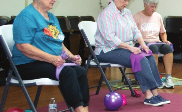 Local senior citizens prepare to perform flexibility exercises in the Columbus Hospitality Center, 516 N. Kansas. Each attendee uses the pictured balls, weights, stretch bands, and chairs to assist with their twice-weekly workout regiment. Pat Niggemann serves as the group’s leader. Photo by Jacob Spencer.