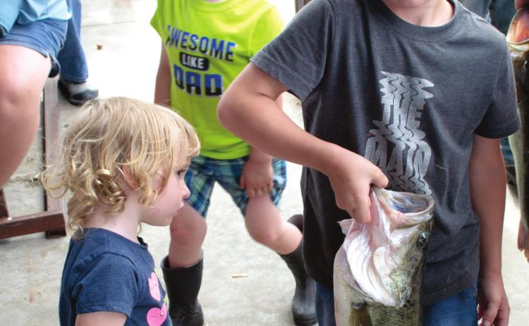 Looking as though she has never seen a fish like that, Karlie Duy admires the bass caught by Wyatt Patton at the West Mineral Eagles Free Fishing Contest held Saturday. There were 325 entries into the contest this year.