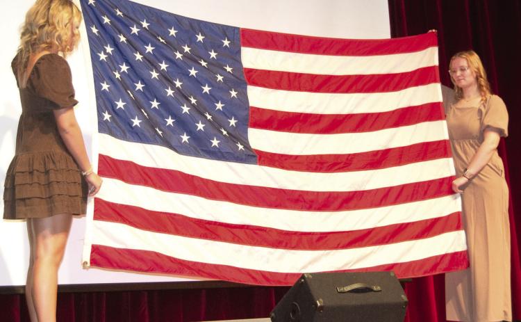 Flag bearers Kenadie Carter and Chloe Rogers ended the Veterans Day program by folding the flag as Mallory Thompson and Lydon Lovesee played “Taps.”