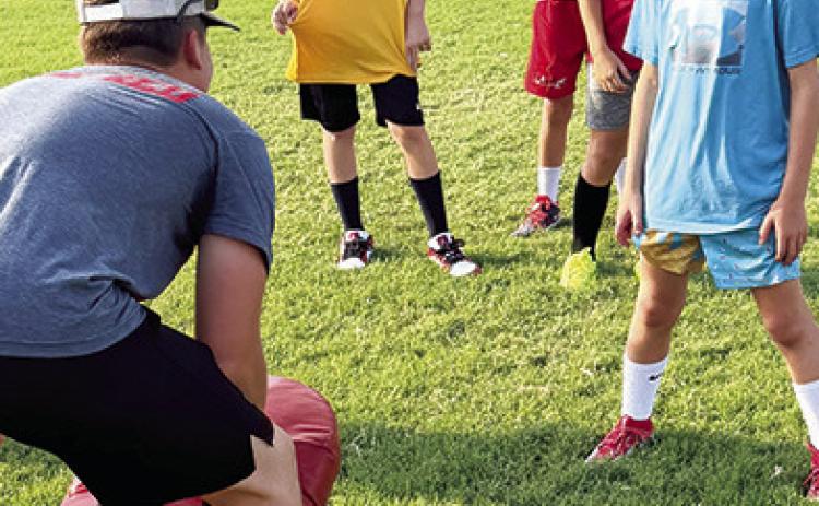 Brody Carter, Titan Junior, helps Kolt Crain, Drake Hamilton, Abel Ellison and Lee Snow with their drills during workouts, Thursday at Titan Stadium. The camp was held for tackle and flag football players in USD 493 grades three through six.