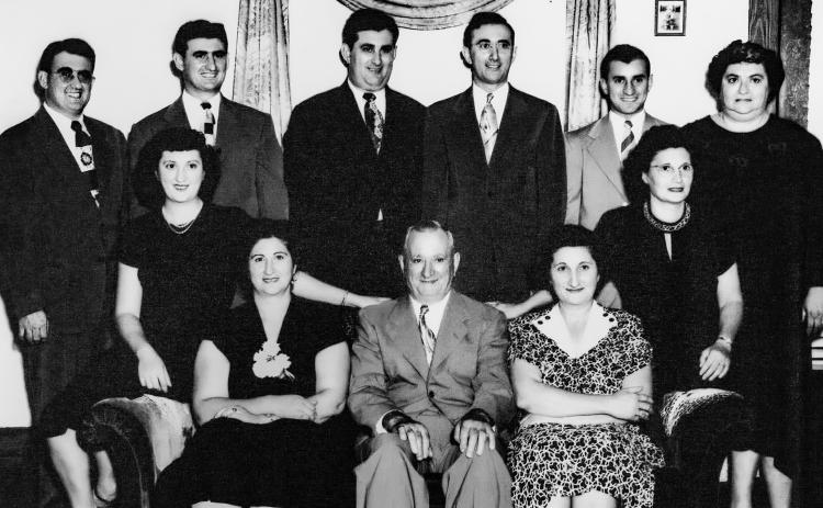 The Pete Ferraro family is prominently featured on the front wall of the Gay Parita ballroom in Carona. Shown are back row left to right, Jim, Frank, Joe, Pete Jr., Mike and Minnie Parise. On sofa left to right Edith Sachetta, Pauline Ducrous, Pete Ferraro Sr., Lily Getto Annie Decicco.