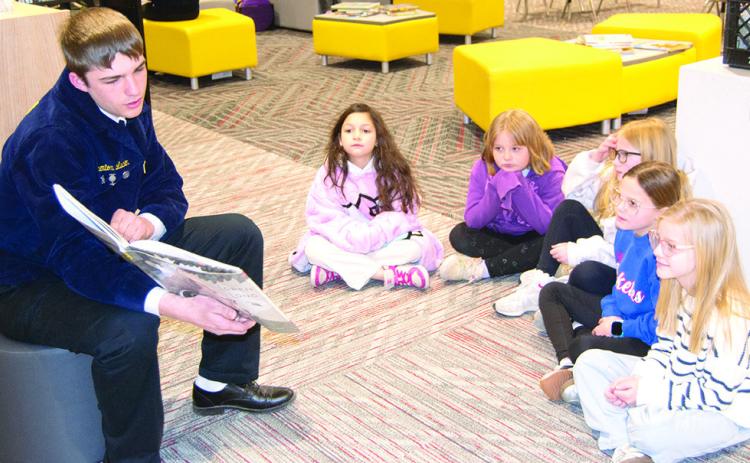 Columbus High School FFA member, Trenton Lacen reads to Amyx Evans, Taylynn Midgett, Brynn Bownan, Harley Sherrill and Adeline Salas, Caitlin Creech’s third graders at Central Elementary. Reading took place at the Central Elementary library as part of national FFA week. News Report photo by Tanya Woolsey.