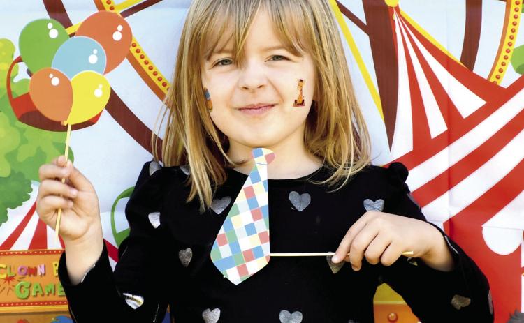 Park elementary kindergarteners celebrated the end of the school year with some last minute carnival fun. Teachers set up and launched a mini carnival at the school including multiple activities. They had a tattoo station, catch the ducks station, boardwalk game, outdoor tic tac toe, ribbon wand fun and popcorn and cotton candy. Meredith Moore shows her tie and balloons in front of the carnival poster. Photo by Tanya Woolsey.
