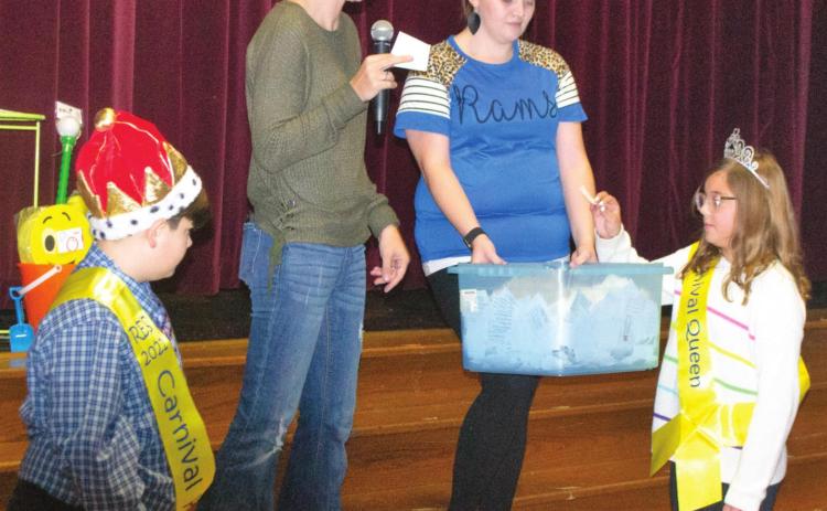 First Grade Teacher Carli Miller stands on stage in Riverton High School’s auditorium with the PTO Carnival King Colton Bebee and Queen Paige Boyes. The students are seen helping her draw tickets for prize money awarded to three of the event’s lucky attendees. Photo by Jacob Spencer.