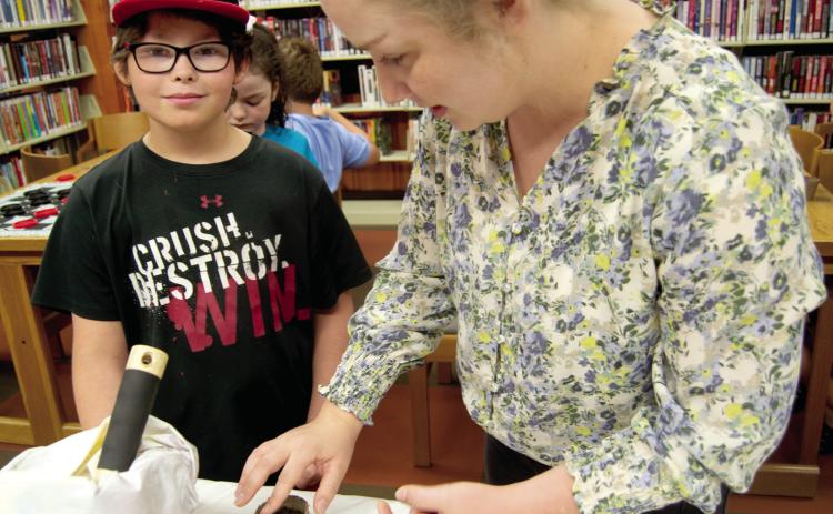 Tucker David watches as Cherokee County extension agent Kate Fluckiger puts seeds in a grow cup during the Garden Program for Kids at the Weir Library on Thursday. The youngsters were given soil and seeds and instructions on caring for the plants.