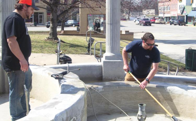 Spring cleaning is beginning at the Cherokee County Courthouse. Nate Davis and Mike Clark got to work scrubbing out algae and limestone deposits around the courthouse’s fountain on March 15. Photo by Jacob Spencer
