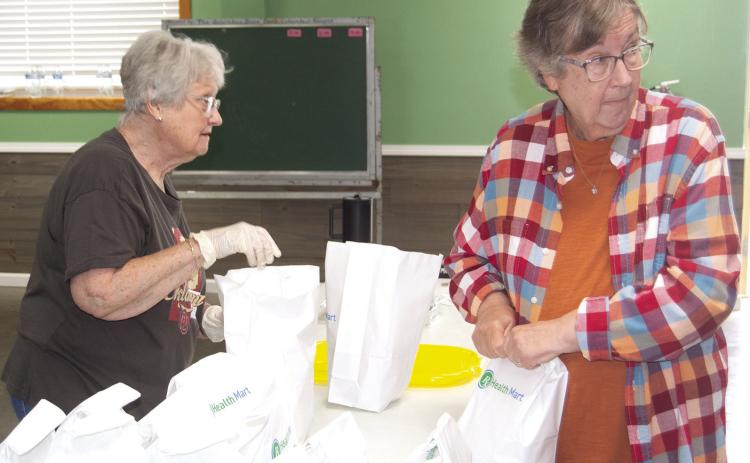 Linda Garrison and Cheryl Vanatta were bagging to go orders at the fundraiser for Jenny Shilts recently. News Report photo by Tanya Woolsey.