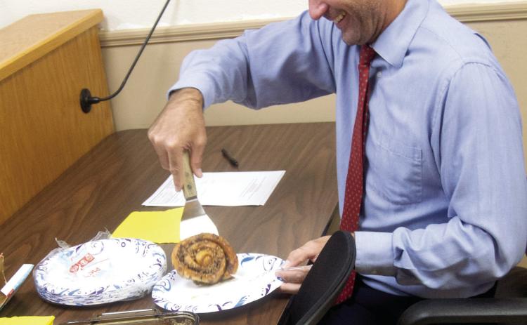 County Attorney Nathan Coleman digs into cinnamon rolls as the Commissioners held their last regular meeting with Coleman as the County Attorney.