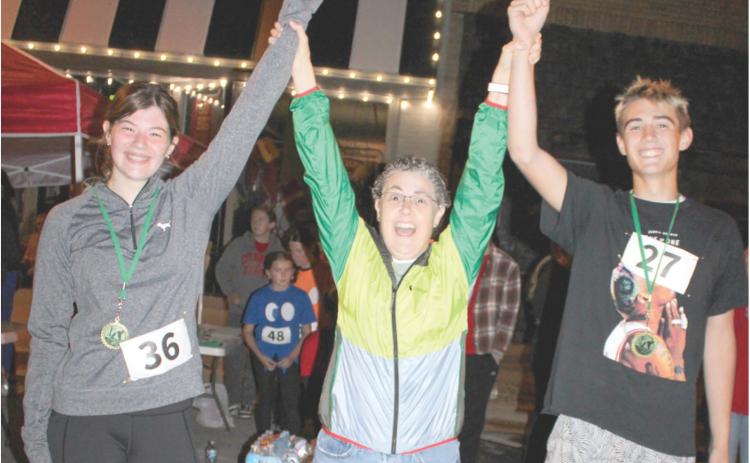 Band director Gae Phillips congratulates two of the winners of the Zombie run sponsored by the Columbus High School Band. The Zombie Run is looked forward to by many runners in the area.