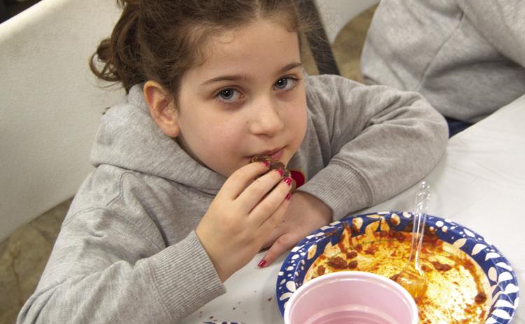 Nothing like finishing a meal with homemade cookies, says Finley Sanders after enjoying spaghetti during the Jon Tavenaro benefit at the Community Center in Weir on Saturday. The successful benefit included a large silent auction.