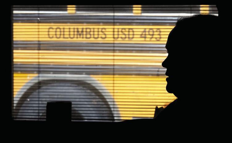 The silhouette of third grade teacher Bekah Noel, at the end of a school day watches her students load onto busses. AP Photo Nick Ingram.