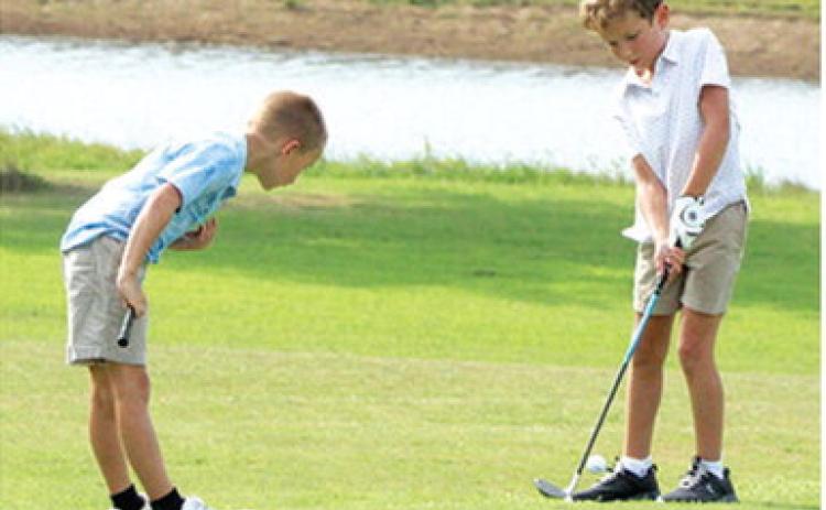 Jack Koons has a watchful eye in Hollis Havercamp’s chip shot during the Thursday junior golf clinic at the Brush Creek Golf Course. Lady Titan Sophomore, Cali Carpino and Titan Senior, Easton Long shared their talents and knowledge with the campers during the multi-week camp.