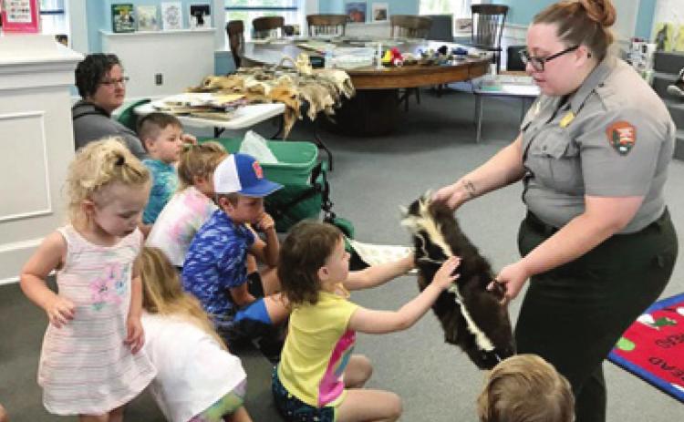 Park Ranger Sarah Martin with George Washington Carver National Monument in Diamond, Mo., brought an array of animal pelts to show the children at the Johnston Public Library Tales and Tails program. One of the pelts was from a skunk. The next program is scheduled for June 24 and a pet show is planned. Photo by Dee Riley.