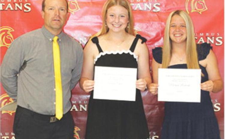 Seniors, Trinity Green and Morgan Richards, received the Tom Goettel Scholarship in the amount of $1,000 each from USD 493 Staff Member, Jerry Smiley, during the 2026 Senior Assembly, May 15, at the Columbus Unified High School Gymnasium.