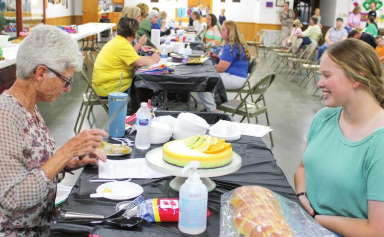 Emma Walker, 4-H member, speaks with one of the judges during the foods show. Walker explained her projects to the judge, discussing ingredients, methods and other facets of her entry.