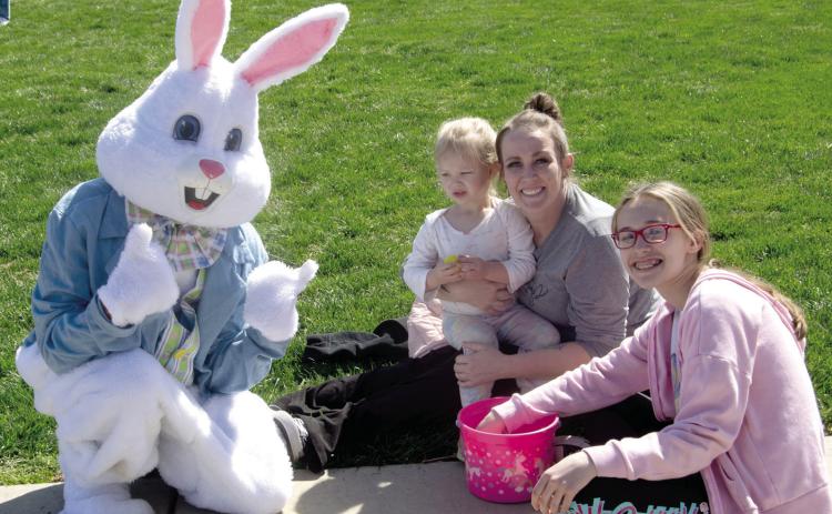 A visit with the Easter Bunny following the Baxter Springs Kiwanis Club Easter Egg hunt at the High School on Saturday. Piper McMillen is held by Amanda Maghe while Josie Stewart checks the egg basket.