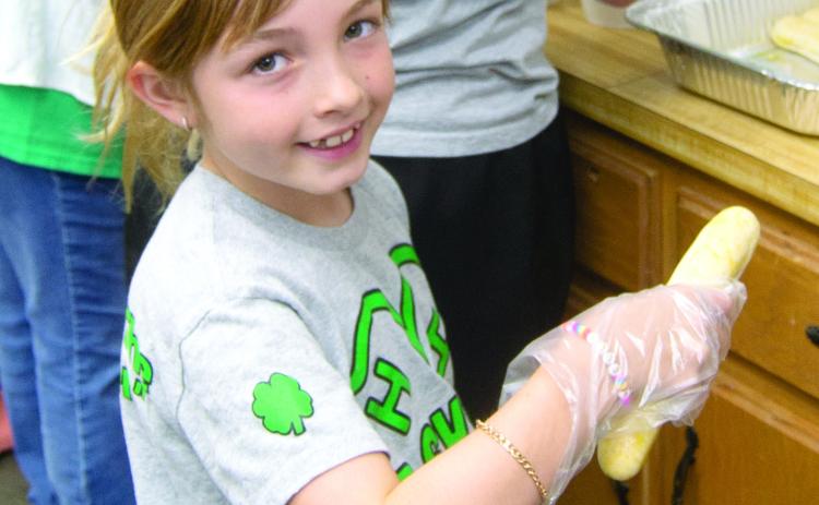 Everybody was helping at the very successful 4-H building fund raiser June 7. The funds will be used to remodel the building. Elle Jesse had the job of putting bread sticks in the spaghetti dinner.